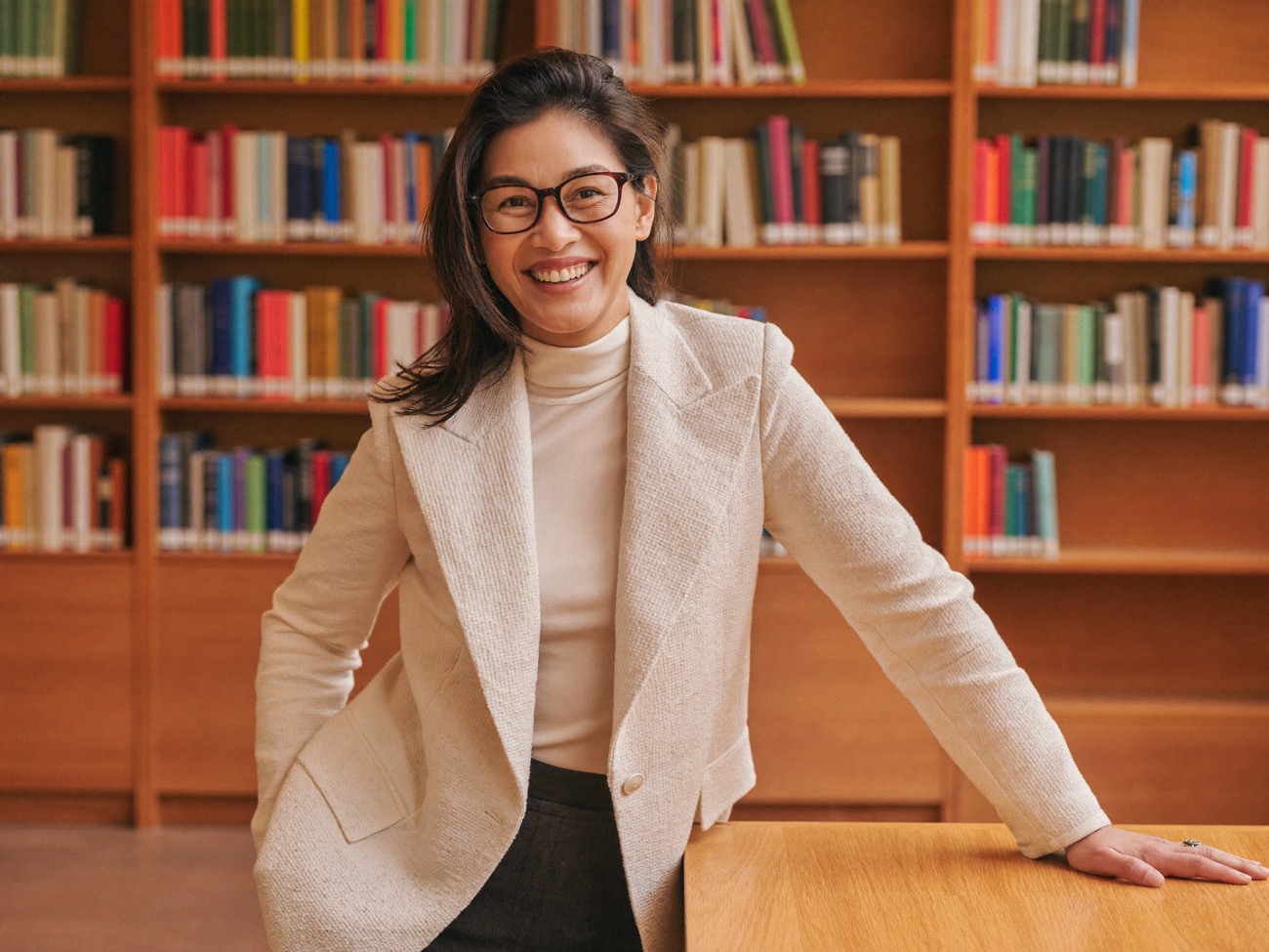 A professor smiling in her office in front of full bookshelves.